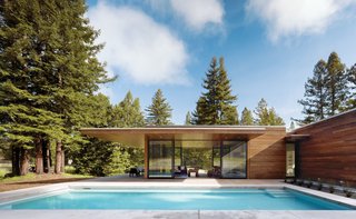 10 Modern Glass Homes - Photo 5 of 10 - Two linked 1,000-square-foot pavilions are greater than a sum of their parts. The simply detailed, taut, flat-roofed home’s two wings form a T-shape. One wing runs north to south, parallel to a pool, and contains the open-plan living spaces.