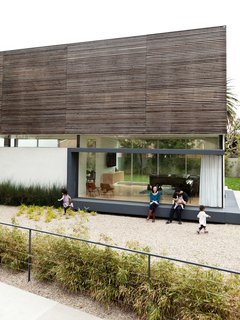 The house sits on a corner lot, which makes the side yard (shown here) also a front yard. Five-and-a-half-year-old Maya (left) and two-and-a-half-year-old Yumi (right) play on the gravel while Mayuko, David, and Shota sit on the bench.