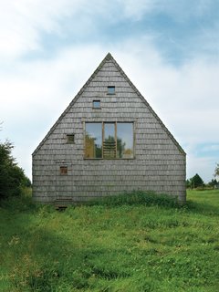 The result: a house that looks like it’s just been dropped into a field, casual, with nary a path leading up to it and a front door that can barely be detected on the red-cedar-shingled facade.