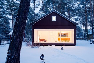 Choosing not to make a big to-do of itself, this cottage blends in with its surroundings. A wall of glass on one end allows a merger of the outdoors with the interiors, while white trim leaves the appearance of a snow-kissed façade year-round. Berlin, Germany. By Atelier st Gesellschaft von Architekten mbHfrom the book Rock the Shack, Copyright Gestalten 2013.