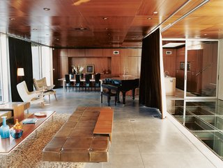 The Jonathan - Photo 6 of 10 - In the humidor-like living room, modern classics like the off-white armchairs by Hans Wegner complement pieces of Segal’s own design, such as the coffee table and long leather seating.