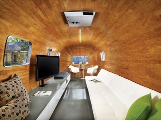 8 Ways to Renovate an Airstream - Photo 3 of 8 - The long sofa, bar, and television were obvious choices for a pre-show hangout, but how to achieve the continuous curve of the revamped Airstream’s interior was not. Baldridge and his team labored to find a kind of wood that would accept the serious bend before deciding on mahogany veneer. As for the new entry, he imagined it as a "modern I Dream of Genie bottle."