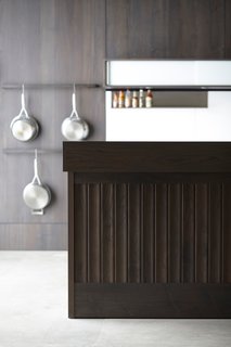What Goes On Behind-the-Scenes at Henrybuilt’s Seattle Test Kitchen - Photo 6 of 8 - The test kitchen is outfitted with their Opencase Wall System, configured with two pot racks and a sliding glass wall unit that includes integrated LED lighting. The Backsplash System is constructed of solid white acrylic and features a stainless steel shelf. Finally, the gray walnut island is finished with an impeccable tongue-and-groove paneling, a recent addition to Henrybuilt’s growing range of products.