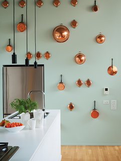Orrill wanted the kitchen to be command central for entertaining, so everything is kept inside minimalist cabinetry—except for the copper pots and pans hanging on the back wall, painted in Pale Water by ICI Dulux Paint. The refrigerator is by Jenn-Air and the faucet is American Standard.