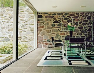 Three stark planes make the dining room a place of sun and shadow: a wall of rock, a floor of bluestone, and a sheer slice of glass. Further adding to the unity of the house, the tubular steel dining chairs were also designed by Breuer.