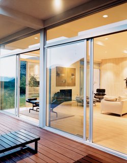 The living room utilizes Eames lounges and a B&B Italia sofa to create a spare but comfortable environment. Sliding glass doors provide ample ventilation.