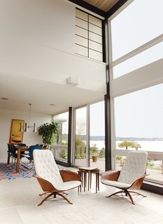 Central to the living room of this Washington home is a pair of George Mulhauser for Plycraft chairs upholstered in sleek white leather. The adjacent dining room sports a Galaxy chandelier from Rejuvenation, a custom table, and Gideon Kramer Ion chairs.