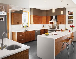 Cost-Effective Family Home in Pittsburgh - Photo 4 of 8 - In the kitchen, Echo pendants from Tech Lighting hang above quartz countertops from Cambria. "The cabinets were a cost-driven solution," Moss says. "The kitchen was developed around Ikea cabinet boxes, but we sourced the semi-custom cabinet front panels through an online retailer, 27estore.com." The range is by Frigidaire and the wall-mounted range hood is by Cavaliere. A pair of Lyra stools by Design Group Italia for Magis round out the space.
