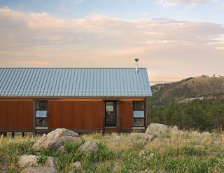 The fire-resistant structure is clad in corrugated Cor-Ten steel that has been left to rust for easy maintenance. Instead of fussy landscaping, the family spread seed for native grasses and wildflowers that they let fill in naturally.
