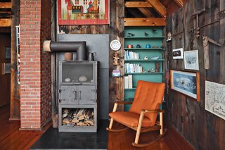 Jens Risom's Block Island Family Retreat - Photo 3 of 13 - Inside the house, a relatively new Rais wood-burning stove is next to a Risom Rocker from Design Within Reach, a 2009 piece from the designer.