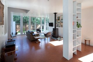 The living room at the front of the house benefits from the privacy afforded from the cedar screen and the light let in by a wall of windows. The wood-burning stove and collection of paintings give the modern home a bit of New England charm.