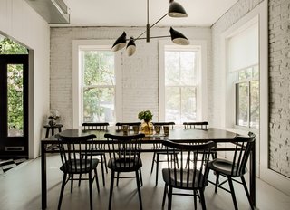 The Torroja pendant light by David Weeks hangs in the dining area, standing in sharp relief to the home’s original brick, now painted white (in Benjamin Moore Paper White) along with the wooden floorboards (in Benjamin Moore Revere Pewter). Radiant heat underfoot means a toasty interior even without a surfeit of textiles. 