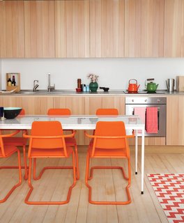 In this custom-built London guesthouse kitchen designed by Studiomama, lustrous vertically clad cabinetry achieves additional depth with the addition of the chairs, which were picked up for $15 each at a local market and powder coated in bright orange.