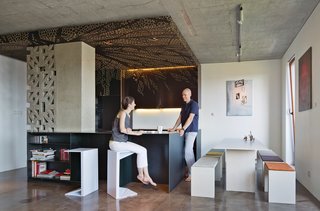 Nix and Novak-Zemplinski, founders of the design firm BioLINIA, in their 1,000-square-foot apartment’s open-plan kitchen, dining, and living space. They had the decorative cabinets and ceiling panels CNC-milled by a Polish subsidiary of the Finnish company Koskisen.