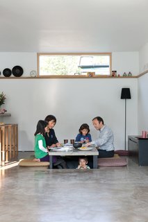 The family sits around, and under in the case of four-year-old Kaz’ma, the sunken table for a snack. Makiko made the covers of the mats her mother sent from Japan by hand. The black lamp is from Ikea.