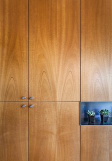 Cabinetmaker Ben Wilborn carefully matched the grain of the cabinets, which hold everything from dishes to a television, while a steel niche for the dining table leaf doubles as a display space.