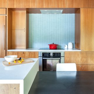 The stools are from Crate & Barrel. The Hobsons chose a geometric-patterned glass tile backsplash by Island Stone. Induction cooktop and oven are by Bosch.