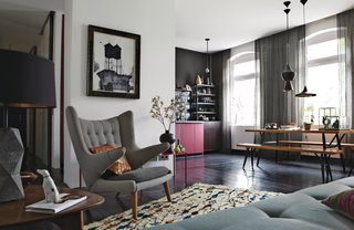 The old wood floors throughout the open-plan space are painted a dark eggplant. The vintage PP19 armchair is by Hans J. Wegner for PP Møbler. The painting above it is by Ruben Toledo, a friend of Peter Fehrentz, the resident. A trio of Tom Dixon lights hangs over the Pirkka dining table, with bench seating by Ilmari Tapiovaara for Artek. The Berber rug is from Morocco, purchased from the Paris shop Caravane.