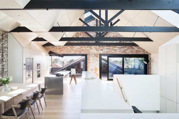 Modern home with dining room, chair, table, and light hardwood floor. “A high-performance, heavily tinted glass was used within the skylights’ double-glazed units to reduce summer heat,” Simpson says. Autex Industries provided the insulation for the year’s cooler months, and the addition of a second, more geometric ceiling hides modern-day electrical and mechanical cords. Photo 5 of Water Factory