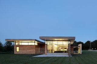 A system of clerestory windows, positioned underneath a cantilevered roof, strategically filters natural light through the interior. A full-height window in the living area provides dramatic views of passing storms.
