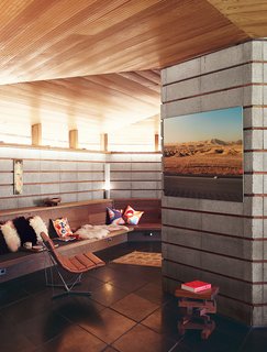 The Midcentury Home That Maintains Its Quirkiness After All These Years - Photo 4 of 9 - A concrete-block wall and a built-in bench line the living room, where a photo by Robbins and a painting by Barry McGee hang near a Catenary chair by George Nelson.
