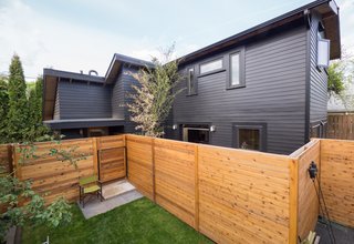 30 All-Black Exterior Modern Homes - Photo 15 of 30 - A client with grown children requested a small dwelling that could double as a work space. Cedar siding painted in Jet Black by Benjamin Moore contrasts the natural wood fencing.