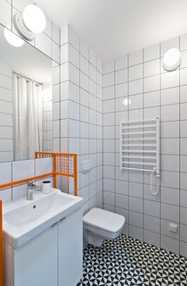 Our Dorm Definitely Did Not Look Like This - Photo 6 of 7 - The bathroom features graphic eye-catching Vives floor tiles surrounded by Opoczno wall tiles and clean white plumbing fixtures. The custom-designed orange sink frame adds a whimsical pop of color.