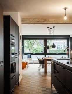 Our Editor Sets the Kitchen and Bath Benchmark - Photo 2 of 6 - A German family's homelife takes shape around their modern kitchen. The residents selected a steel countertop to contrast the matte-black island and cabinets from Vipp. At mealtimes, the family gathers at a Bigfoot table from e15, which is surrounded by vintage Eames shell chairs.