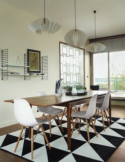 Modern Home Furnished With Flea Market Finds - Photo 2 of 17 - The dining table is from French retailer AM.PM., the pendants are by Him + Her, and the shelves are by Tomado Holland. An Ikea rug echoes the geometric motif found throughout the apartment.