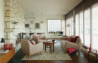 Modern Home Furnished With Flea Market Finds - Photo 3 of 17 - Deau retained original details, like the stone fireplace in the living area and the Jean Prouvé lamp mounted onto it. Vibrant throw pillows by Nathalie Du Pasquier for Hay offset the neutral sofa and armchairs from Habitat and the Moroccan rug. Vintage English occasional and coffee tables stand at the room’s center. Ceramics and objects from Guillaume Bardet, Jonathan Adler, and Ferm Living accent the space.