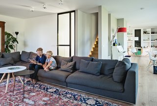 In the living room, Bram and Dirk sit on a sofa by Cocoon near a Persian rug and tables from Leen Bakker. The architects illuminated one side of the stairway leading to the bedrooms.