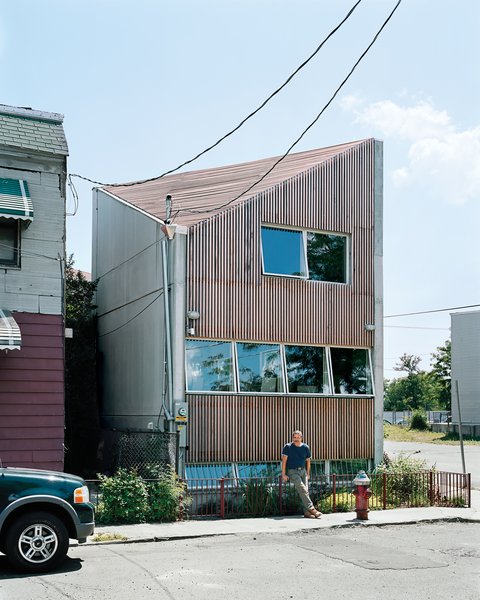 Carpenter poses outside his house, which is shoehorned into a tiny nonconforming lot among a block’s worth of older row houses and a derelict public park.