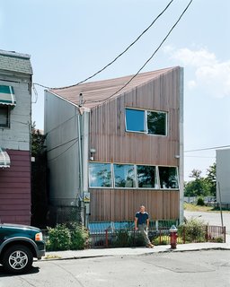 Carpenter poses outside his house, which is shoehorned into a tiny nonconforming lot among a block’s worth of older row houses and a derelict public park.