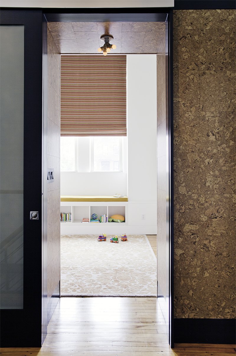 On the second floor, the sliding door to one of the kids’ bedrooms lies flush with a cork-wrapped wall. In the bedroom, a colorful custom Maharam window shade rests above a window seat with a Kvadrat cushion.