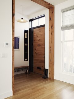 8 Beautiful Home Projects Using Reclaimed Wood - Photo 3 of 8 - Even a few pieces of salvaged lumber can have a big impact. This entryway in a Brooklyn townhouse, renovated by Bangia Agostinho Architecture, reused hemlock fir joists from the existing building structure as casework around the main entry door. The trim has a simple, modern profile, ensuring that it makes a contemporary statement. In the entryway is another repurposed piece of wood that was charred in a fire more than 100 years ago. It has since been painted and repainted—creating a unique patina and texture—and transformed into a bench.
