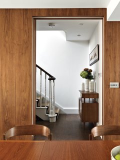 Home of the Brave<br><br>In the ground-floor eating area, the design team wrapped the walls in rich walnut to instill warmth often found in mid-century homes. "Sometimes one bold move is enough. Be brave with fewer statements," Kiely advises. "Go for the big thing rather than lots of little things." Kiely’s Upholstered Dining Chairs from her House collection surround a Danish vintage dining table. Her Gloss vases adorn the hallway console, which is also from her House line.
