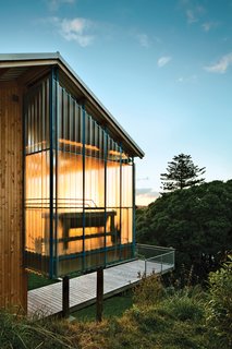 Rookie firm Patch Work Architecture used locally sourced Lawson cypress to clad the exterior of a 970-square-foot house in New Zealand. Vibrant painted accents contrast with the otherwise neutral structure. Steel trusses, painted in a blue hue called Lochmara from Resene, are visible through the fiberglass panels on the veranda. Photo by: Paul McCredie
