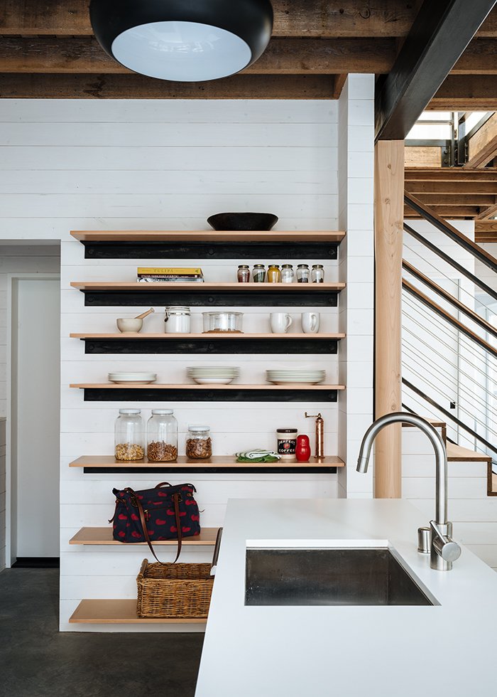 Though small, the kitchen feels generously bright. Its cabinets were custom-built by Bob Clausen, a local craftsman. Curtiss selected sleek faucet fixtures by Santec and a sink by Blanco to complement the white laminate countertops. The stainless steel appliances include a Bertazzoni oven, Fisher & Payel refrigerator, and Thermador dishwasher.