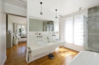 10 Dreamy Parisian Homes - Photo 2 of 10 - "The old living room and balcony on the sixth floor were transformed into the master bedroom with an en-suite open bathroom," Hammer said. Flos lighting illuminates the space above the vanity.