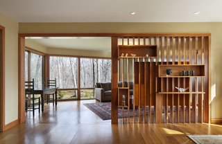 The homeowners are avid collectors of Haitian art and exhibit some of their collection within the Douglas fir slats. A Crate & Barrel Axis sofa pairs well with vintage pieces including a farmhouse table, chairs, and rugs.