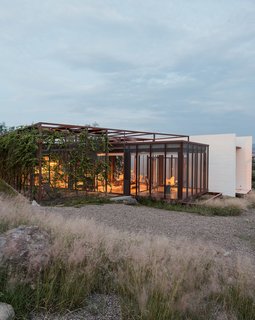 Two art studios adjoin a central volume at this work/live residence built from terracreto (sustainable concrete), glass, and painted steel just outside of San Miguel de Allende, Mexico. Residents Austin and Lida Lowrey, retired design and museum professionals, collaborated with their two daughters—Sheridan, an artist, and Elizabeth, an architect—to design the structure as a place for creative contemplation.
