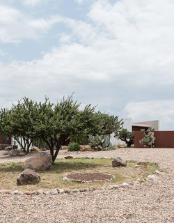 Crushed stone paths and native plantings, including cacti, wildflowers, and grasses, encompass the surrounding landscape. 