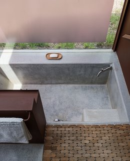 In Lida's studio, terrazzo and granite floors blend seamlessly into a sunken bath, paired with a steel storage unit and a wooden Moroccan bath mat from Insh'ala, a local antique store.