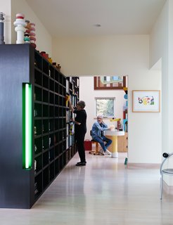 Thank Sottsass for the Most Memphis House Imaginable - Photo 7 of 14 - Sottsass designed a shelving unit around the couple’s large collection of vintage radios. "We have lots of collections," says Lesley. "A Pez collection, a chair collection, a perfume collection...Ettore gave us a choice and said we could pick one to have up on display." A series of the late designer’s Mini Totem earthenware sculptures sit atop the unit. The neon green light accent was inspired by the fluorescent works of artist Dan Flavin. To the right is a First chair from 1983 by designer Michele De Lucchi, who cofounded Memphis.