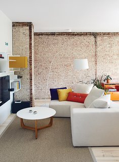 The living room is furnished with a Vita modular shelving system from MDF Italia, a Lili coffee table by Add Interior, and a custom sofa by Linea P International. The Dot cushions are by Hay.