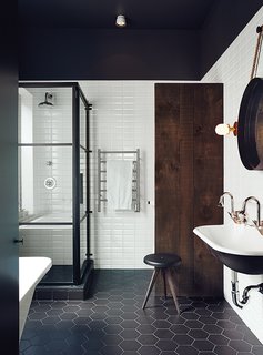 In the master bath, a dowdy tub was replaced with a standing shower designed by Di Ioia and Bédard and manufactured by Linea P International. The wall and floor tiles are by Ceragres, and the sink, tub, and towel rack are by Aqua Mobilier de Bain.