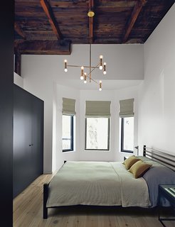 The master bedroom includes an armoire by Kastella and a chandelier by Lambert & Fils. A portion of the ceiling was pared back to expose the underside of the original roof.