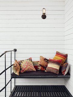 Atop the spiral staircase, a custom iron bench is festooned with Turkish throw pillows from SophiesBazaar.