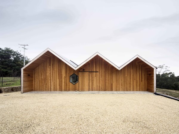 Crump played with the traditional gable roof form common to Australian farmhouses and transformed it into something entirely modern. The house’s three distinct ridgelines follow each other in succession, their simple contours conjuring a cartoon lightning bolt. The wood cladding covering the exterior also lends the house an impenetrable feel, heightening the surprise visitors experience upon entering and seeing its open, seaside views. Photo of Lookout House modern home