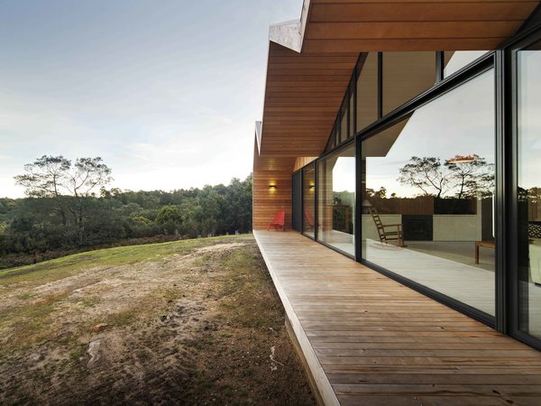 Constructing a largely timber house in a bush fire-prone landscape wasn’t easy. “We had to negotiate with the council and building surveyor,” Crump explains. To solve the challenge, the architect designed an outer, protective skin for the home that’s clad with metal; it pushes beyond the building envelope to provide covering for outdoor living spaces. The inset walls are lined with local shiplap Celery Top Pine. Photo 2 of Lookout House modern home